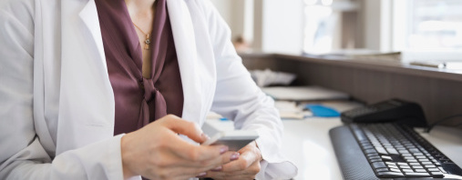 Woman wearing a lab coat on looking at a mobile phone